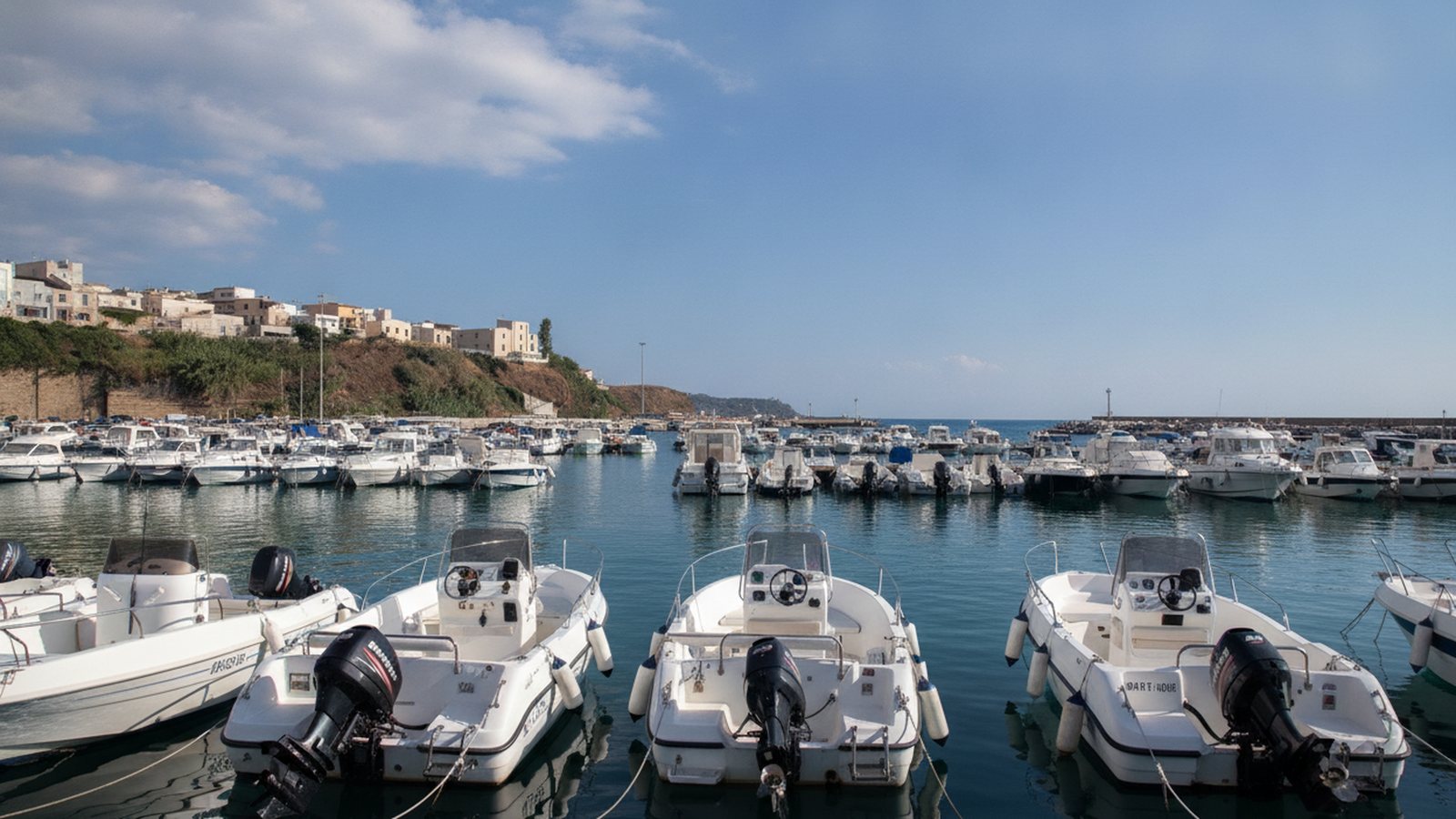 Barche e gommoni ormeggiati nel porto turistico di Balestrate, con il paese sullo sfondo